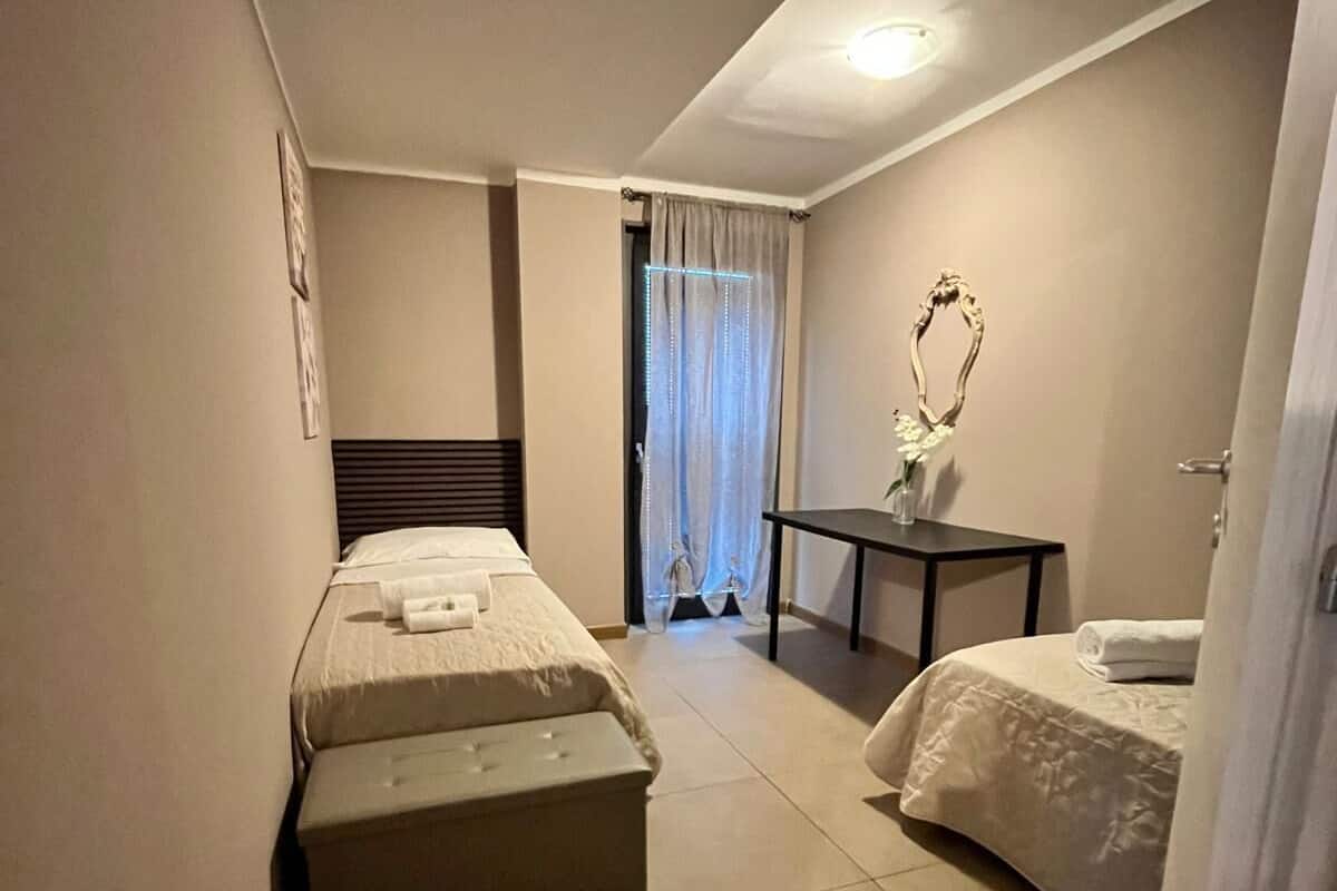 A hotel room with two beds, a small table, and a decorative mirror.