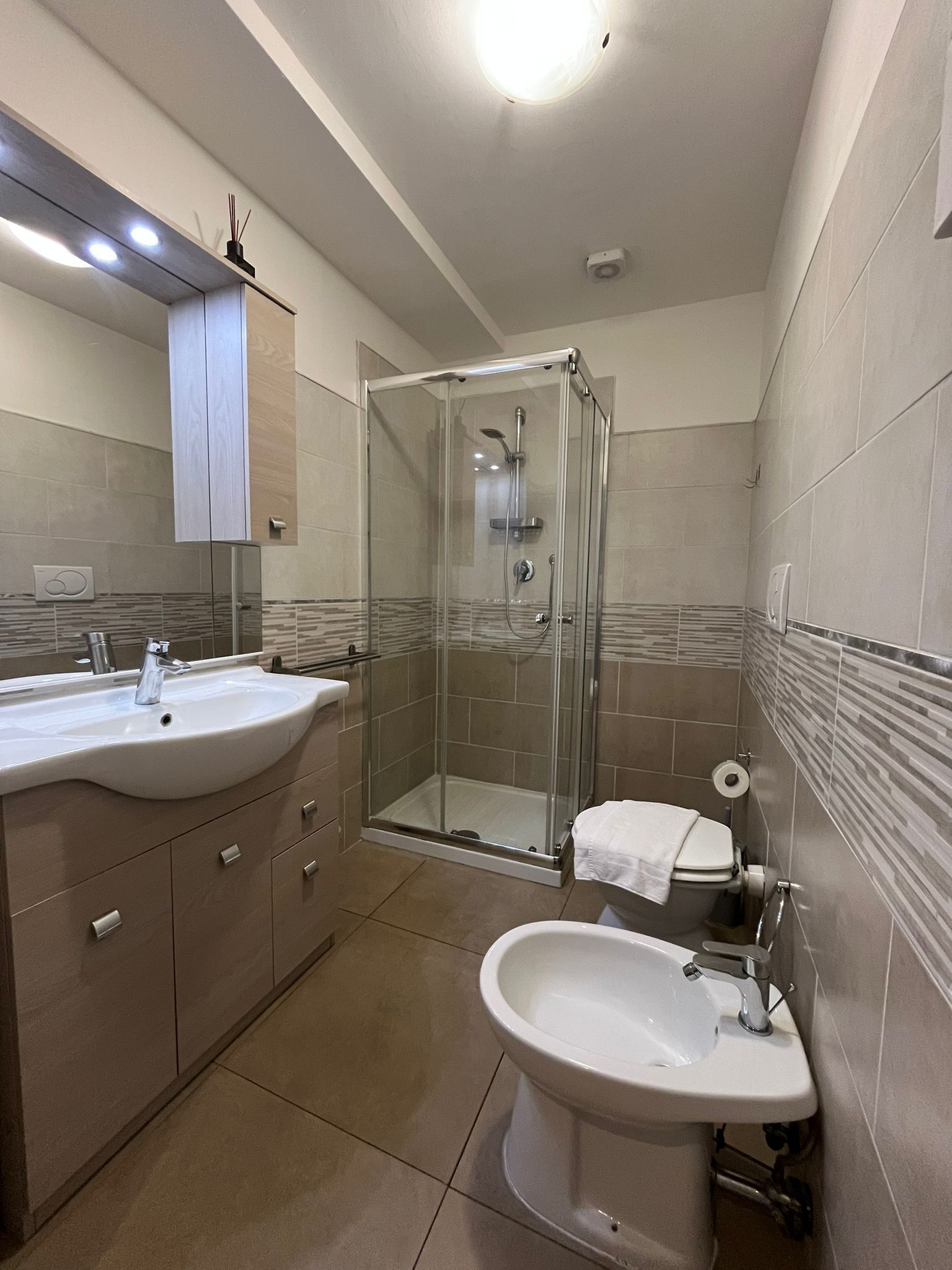 Un baño moderno con ducha de vidrio, lavamanos y bidé.