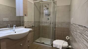 Un baño moderno con ducha de vidrio, lavamanos y bidé.