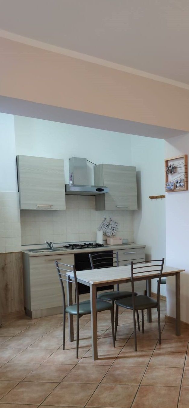 A compact kitchen with a dining area, featuring a gas stove, cabinets, and a tiled floor.