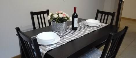 A dining table set with plates, a wine bottle, and a vase of flowers.