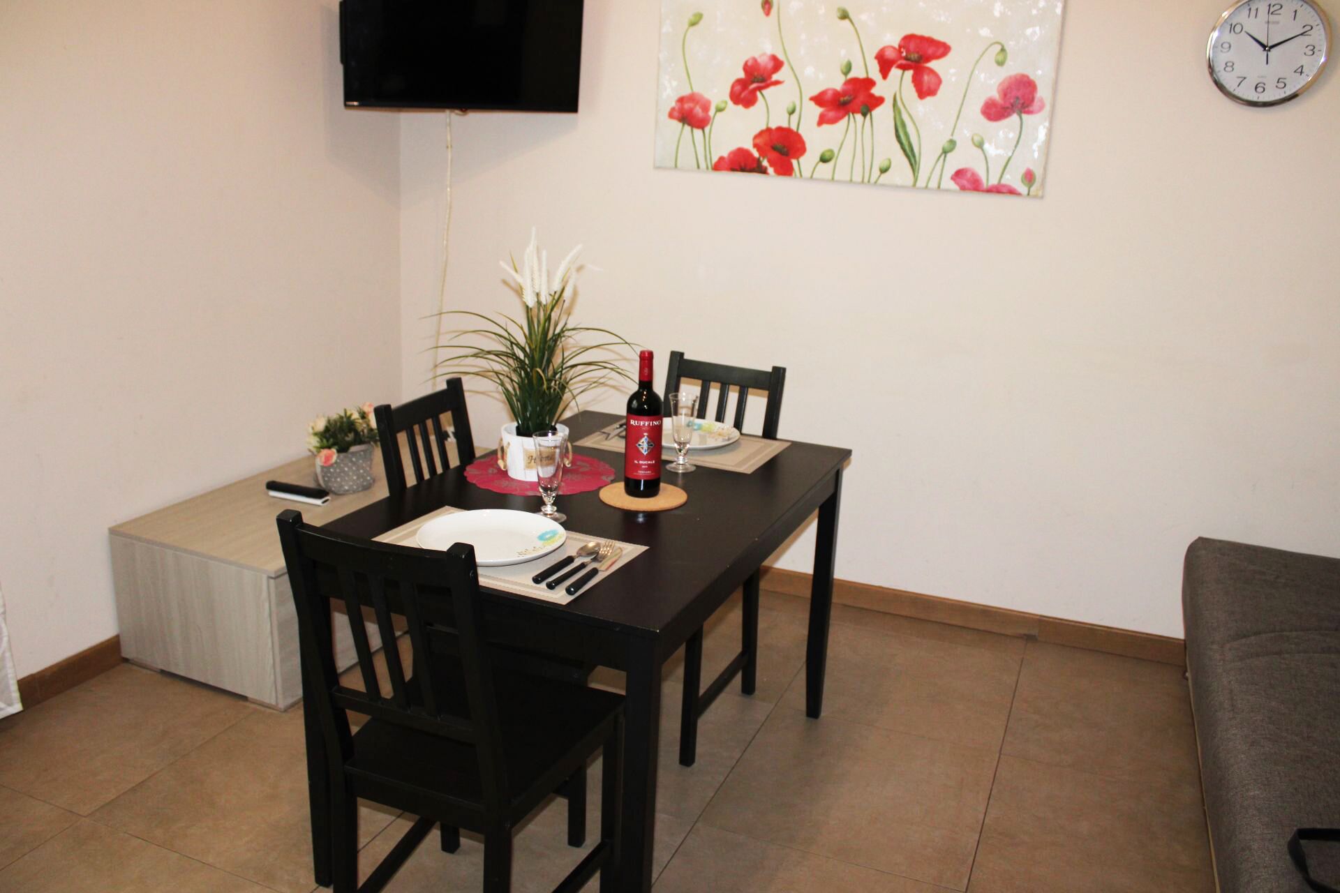 A dining area with a table set for two, a bottle of wine, and a potted plant.