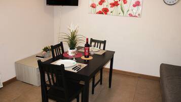A dining area with a table set for two, a bottle of wine, and a potted plant.