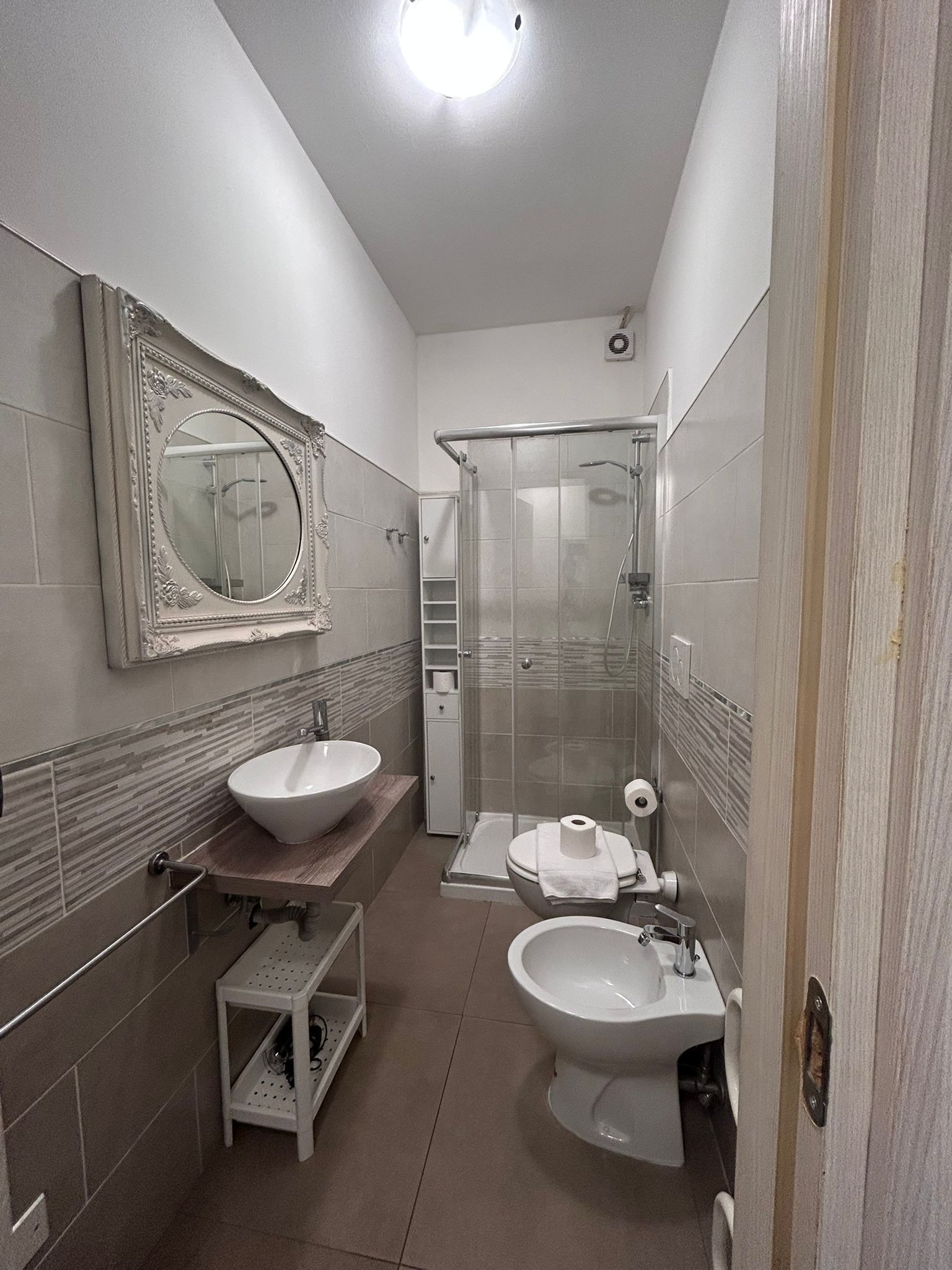 Un bagno funzionale con lavandino, WC e doccia.
