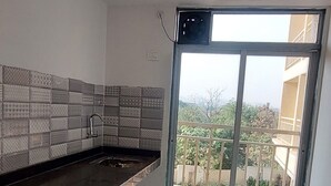 Une cuisine avec un plan de travail foncé, un pare-feu en carreaux et une fenêtre donnant sur un balcon et des immeubles.