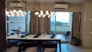Un coin repas avec une table dressée pour quatre personnes, un lustre et une vue sur un balcon.
