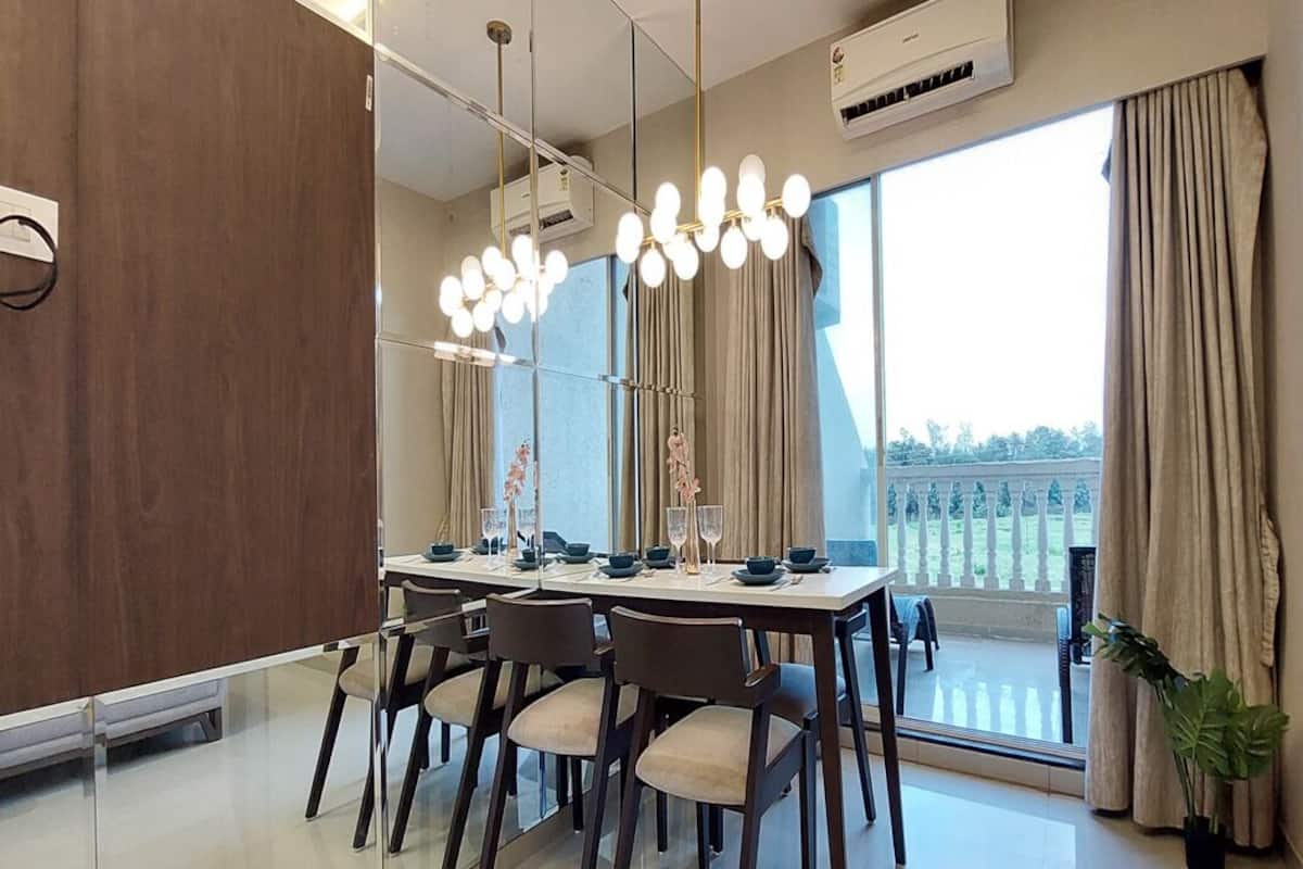 Uma sala de jantar moderna com uma mesa grande posta para seis pessoas, uma janela grande com cortinas e um vaso de planta.