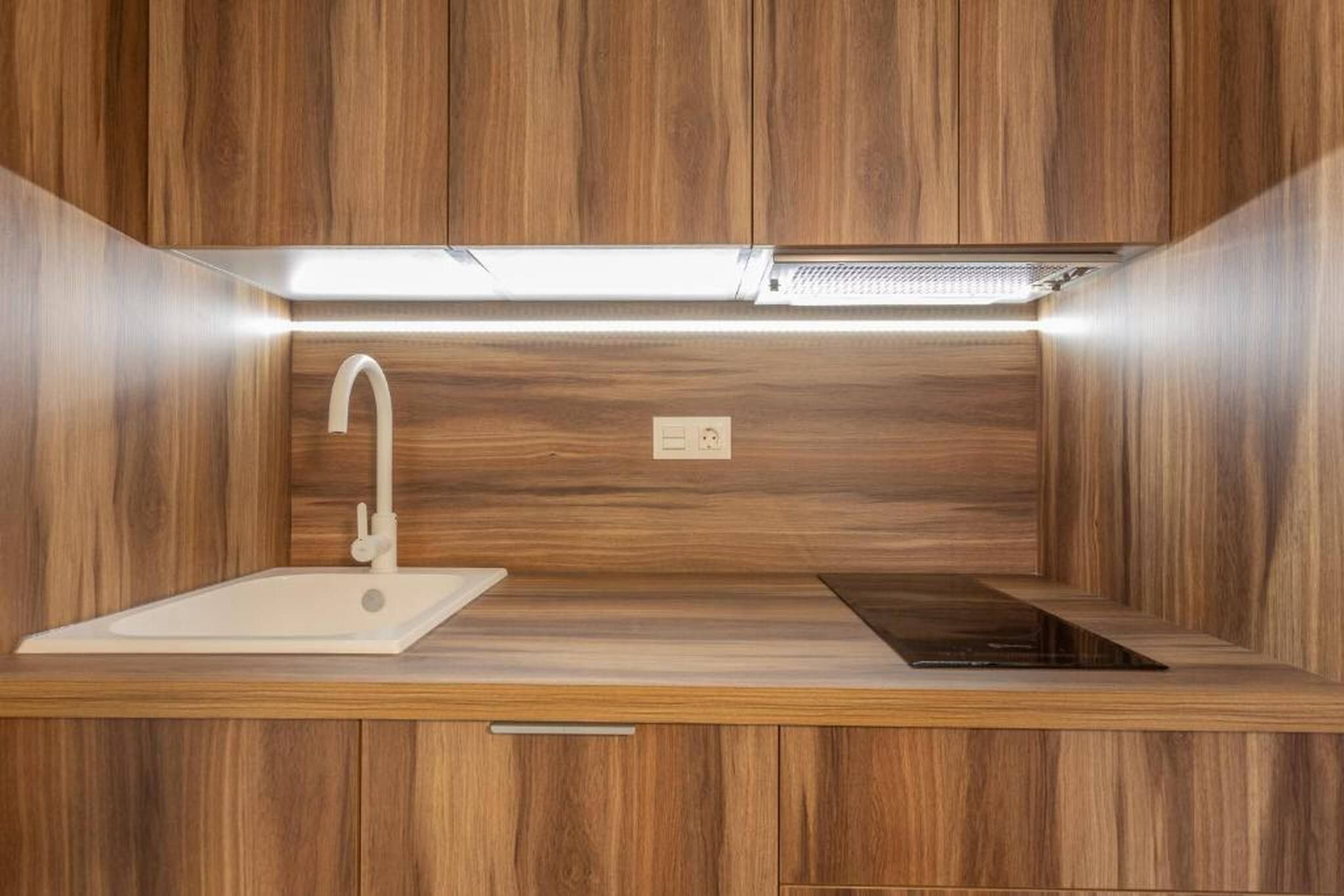 Cocina compacta con lavamanos, grifo y estufa integrada.