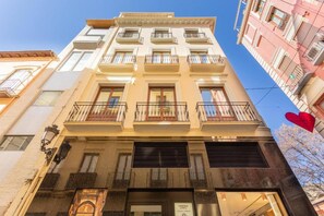 A multi-story building with balconies, a ground-level entrance, and a visible storefront. - Cathedral Royale Suite (granada)