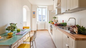 A kitchen with a dining area, featuring a wooden countertop, a sink, and a window with a view of buildings. - Casa Dante in Lucca With 3 Bedrooms and 2 Bathrooms (Lucca)