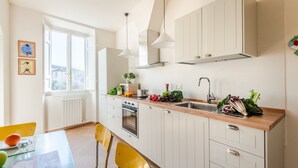 A modern kitchen with white cabinets, a wooden countertop, and a window providing natural light. - Casa Dante in Lucca With 3 Bedrooms and 2 Bathrooms (Lucca)