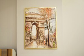 Pintura do Arco do Triunfo em Paris, emoldurada e pendurada numa parede lisa.