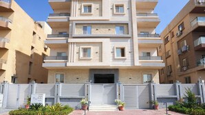 Ένα πολυώροφο κτίριο κατοικιών με μπαλκόνια, μια πύλη στην είσοδο και γλάστρες με φυτά.