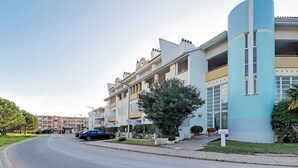 A multi-story residential building with a curved facade, balconies, and a parking area. - Marina Family Duplex with Pool (Loulé)