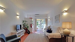 A living room with a sofa, a TV, a lamp, and a plant. - Marina Family Duplex with Pool (Loulé)