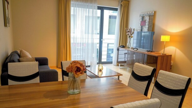 Een hotelkamer met een eethoek, een bank, een televisie en een lamp.