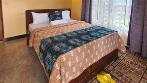 A hotel room with a bed, two wall-mounted lights, a window with curtains, and a pair of slippers on the floor. - Materuni Homes (Moshi)