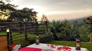 A table set outdoors with a red tablecloth, two wine glasses, and a lantern. - Materuni Homes (Moshi)