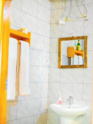 Une salle de bain avec un lavabo blanc, un miroir et un porte-serviettes.