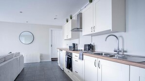 Una cocina moderna con armarios blancos, una encimera de madera, un fregadero y un espejo redondo en la pared.