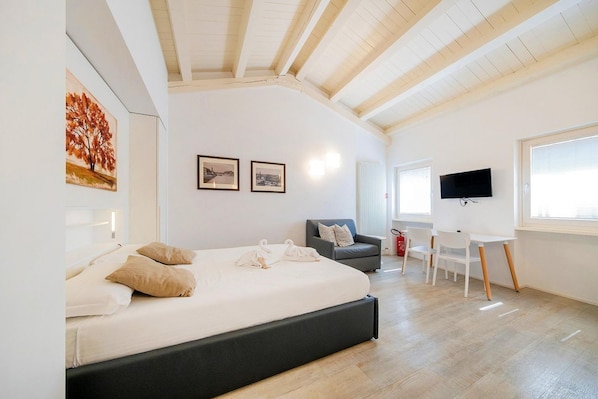 A bedroom with a bed, a TV, a desk, and a chair.