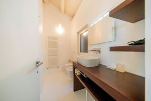 A modern bathroom with a white sink, a mirror, and a wooden vanity.