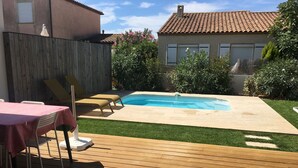 En trädgård med en pool, ett trädäck och ett bord med stolar.