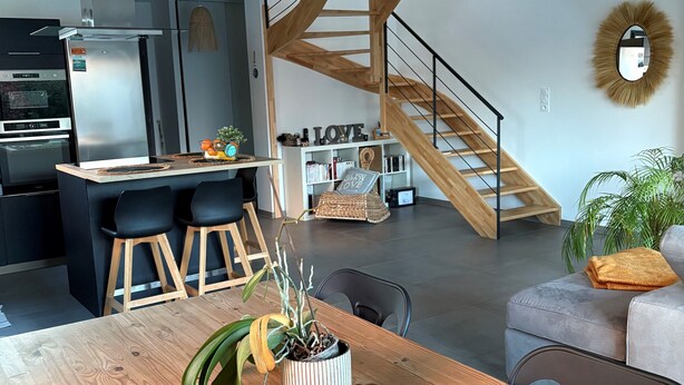 Ett modernt kök med en inbyggd ugn och en trätrappa som leder upp till en övre våning/ett loft.