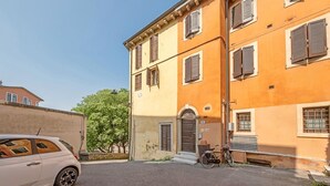 A two-story building with a beige facade, a door with a small porch, and a bicycle parked outside. - ApartmentsArena - Zini Studios - 1 (Verona)