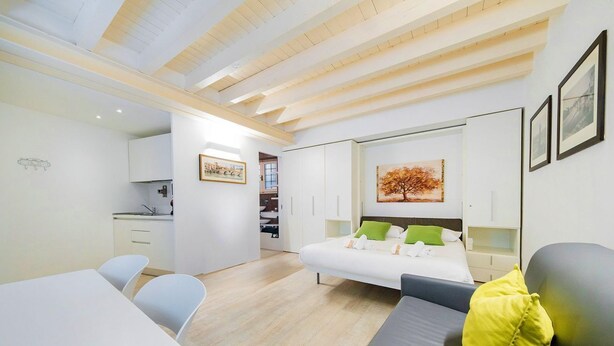 A modern room with a bed, a sofa, a dining table, and a kitchen area. - ApartmentsArena - Zini Studios - 1 (Verona)