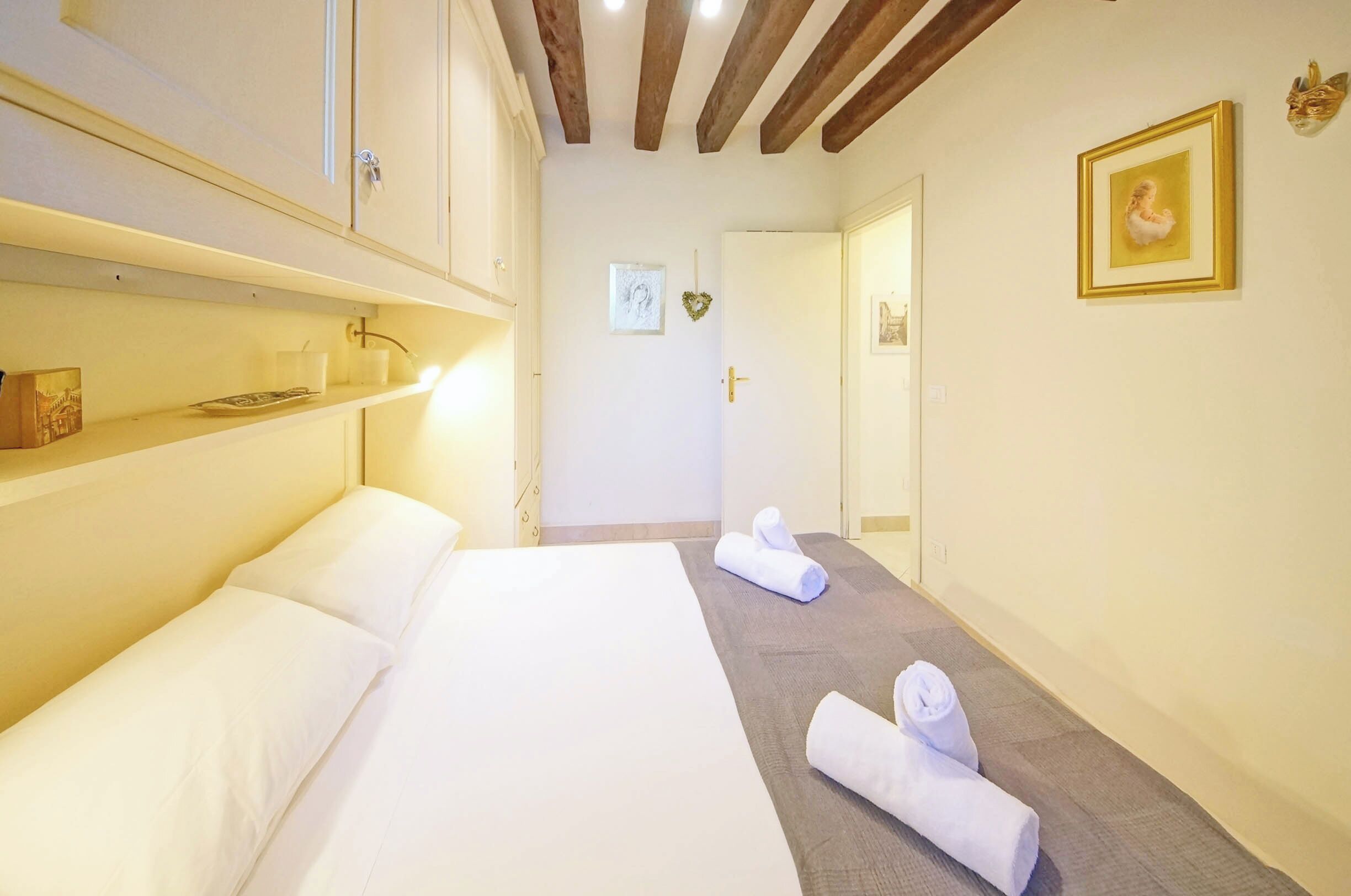 Quarto de hotel com cama, escrivaninha e cadeira. Toalhas no chão.