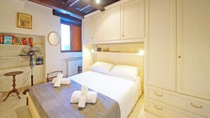 Een hotelkamer met een bed, nachtkastje, ventilator en een kledingkast.