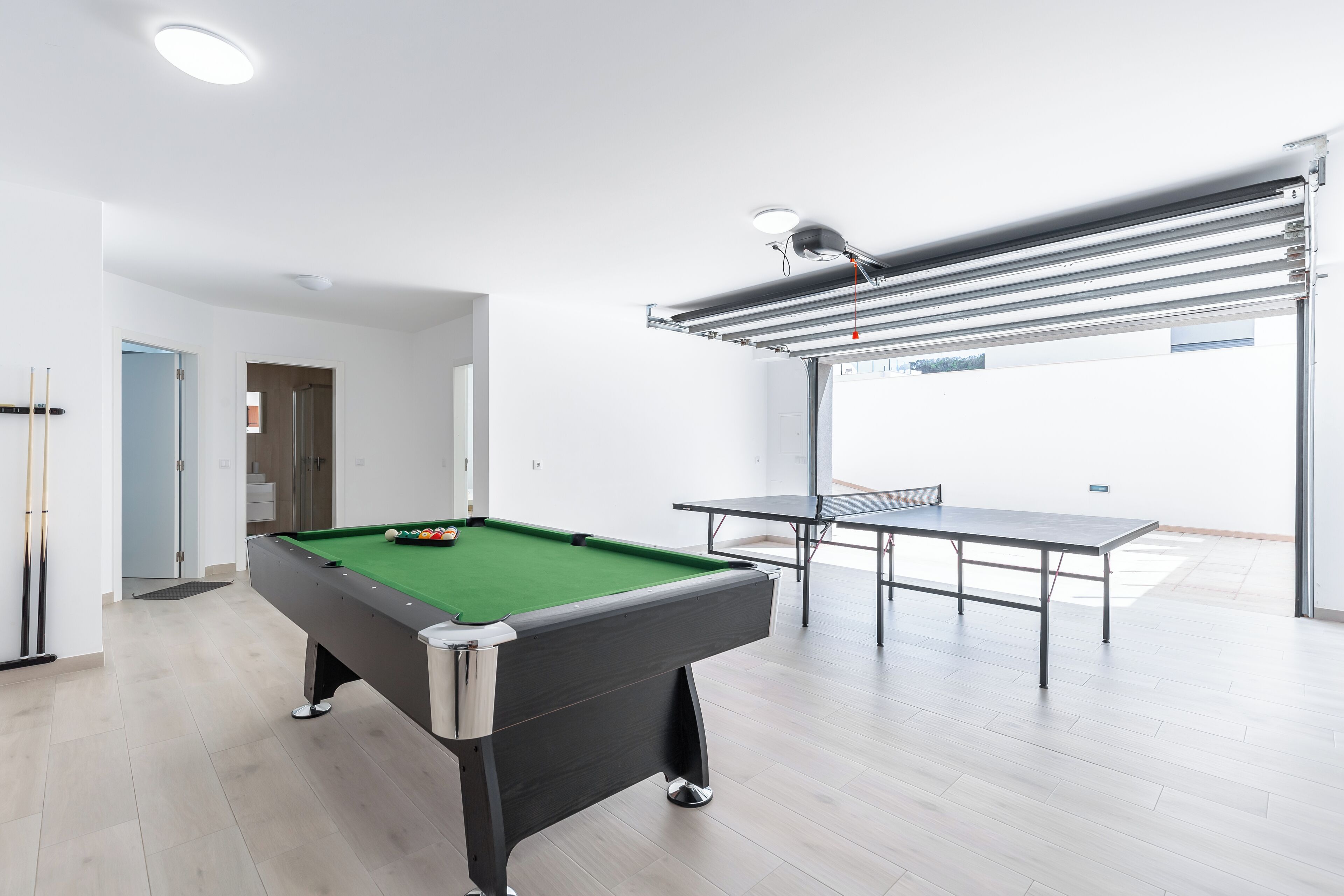 A spacious room with a pool table, a billiards table, and a ping pong table.