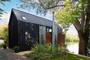 Un edificio moderno nero con tetto spiovente, una piccola finestra e un portone.