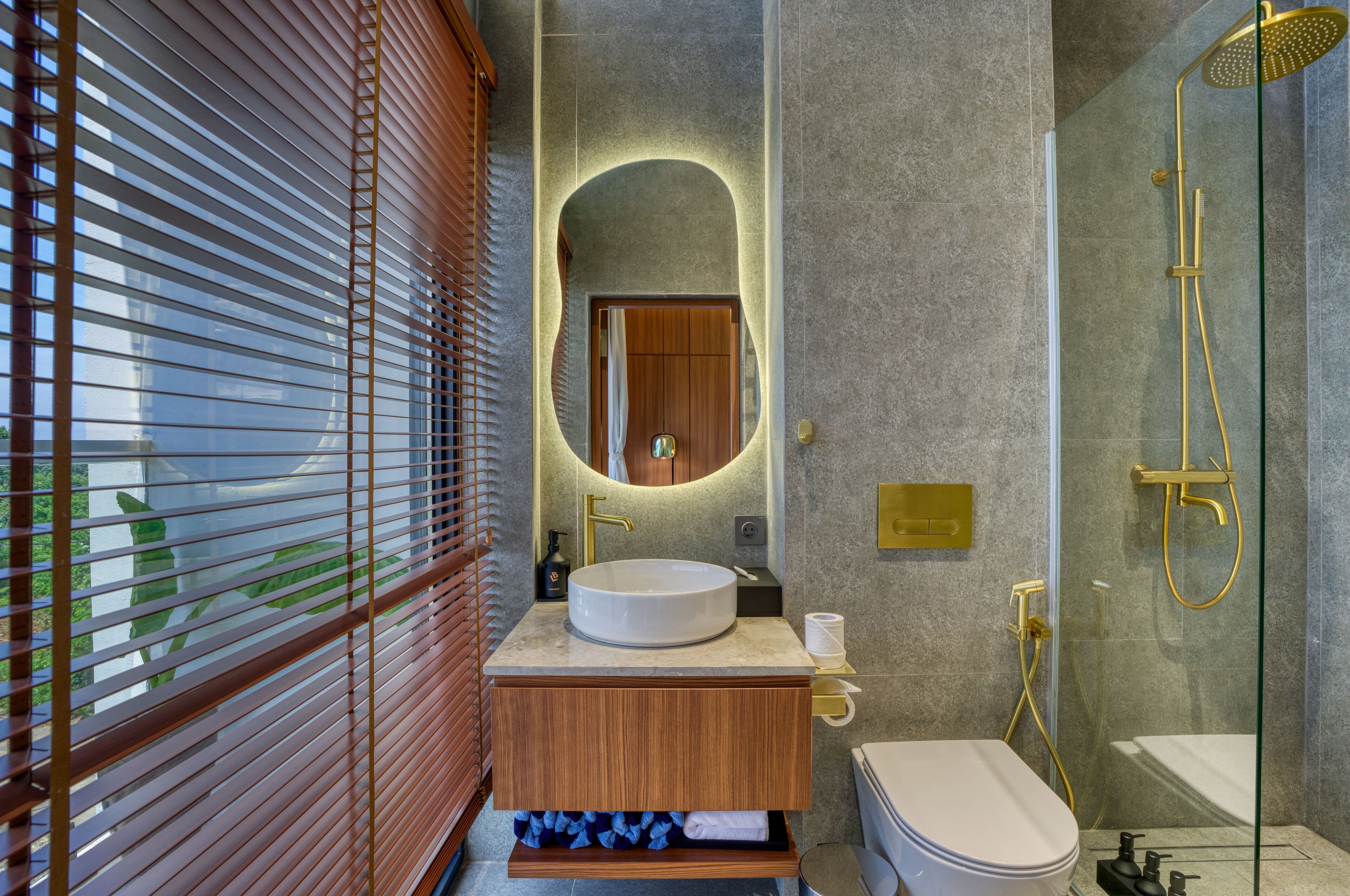 A modern bathroom with a round sink, wooden vanity, a glass shower enclosure, and a large mirror.