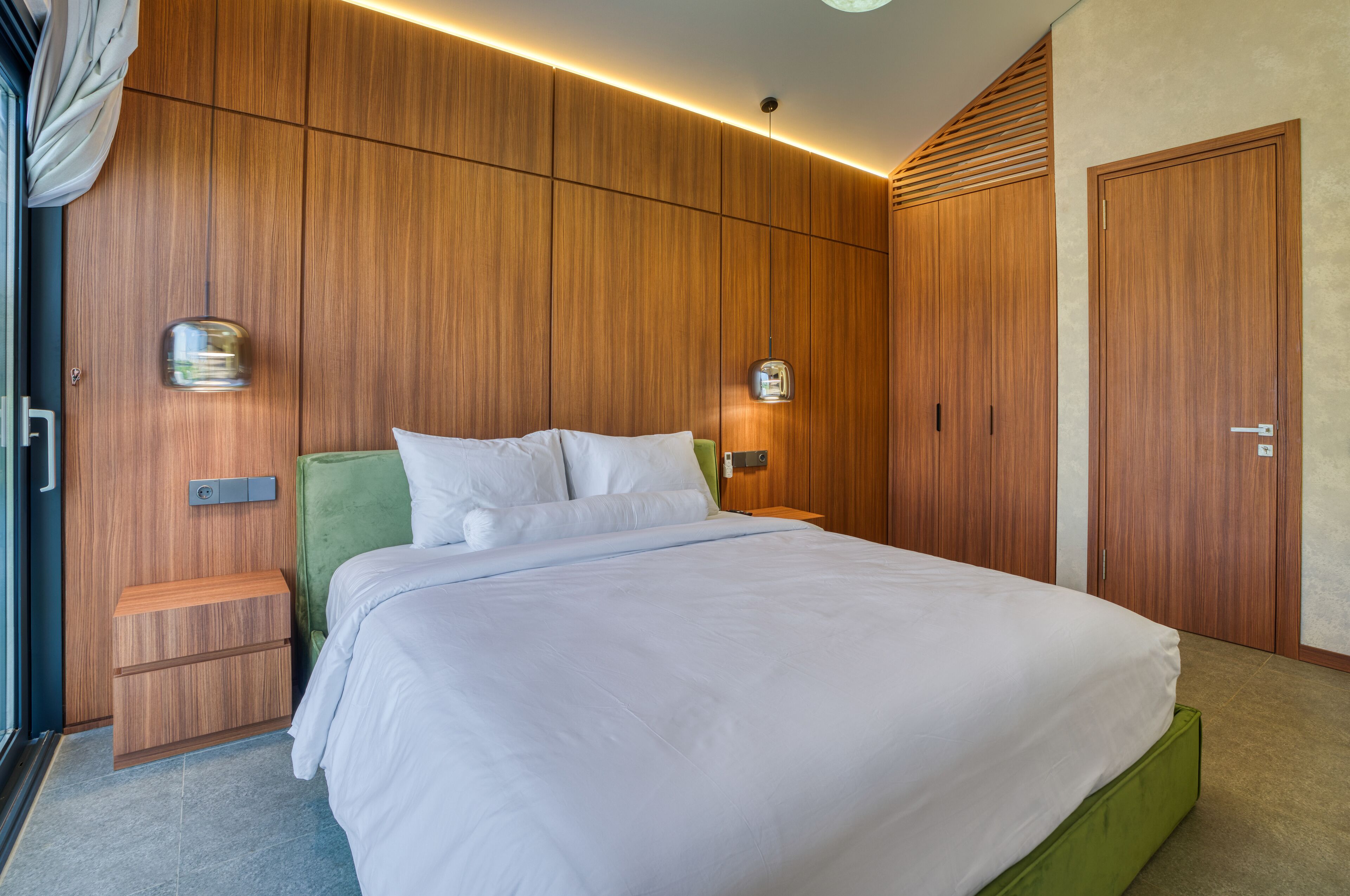 Ein modernes Schlafzimmer mit einem großen Bett, Holzwandverkleidung und integrierter Beleuchtung.