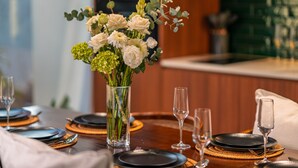A dining table set with black plates, clear glasses, and a centerpiece of white flowers in a clear vase. - U Villas Pandawa (Kutuh)