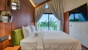 A hotel room with a large bed, wooden panel walls, a green headboard, a bedside table with a phone, and a window with curtains. - U Villas Pandawa (Kutuh)