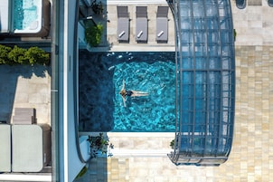 Una piscina techada, una piscina al aire libre, sombrillas