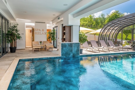 Una piscina techada, una piscina al aire libre, sombrillas
