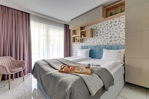 A hotel room with a bed, a chair, a tray with food, and a window with curtains. - Angielska Grobla City Center by Lion Apartments (Gdansk)
