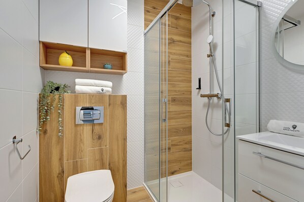 A modern bathroom with a glass shower enclosure, a toilet, and a vanity with a mirror.