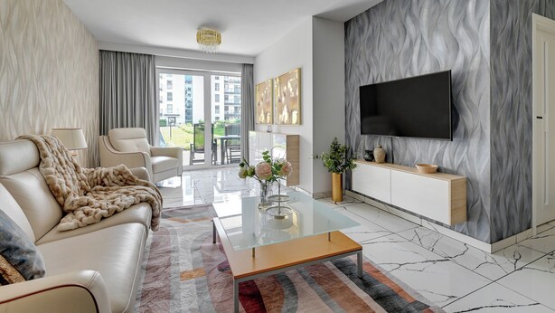 En moderne stue med sofa, sofabord og fjernsyn.