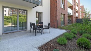 En moderne lejlighed med balkon, en terrasse med udendørs møbler og et haveområde.