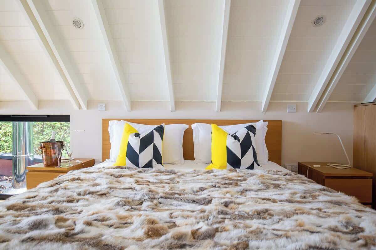 Un dormitorio con una cama grande, cabecera de madera y vistas al exterior.