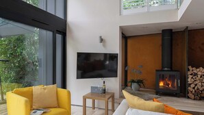 Una sala de estar moderna con televisor, sofá y estufa de leña.
