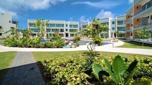 A modern hotel with multiple floors, a swimming pool, and well-maintained gardens. - Luxury Waterfront 3bed Penthouse w/Rooftop Terrace (George Town)
