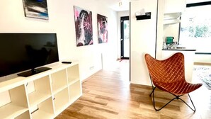 A modern living room with a flat-screen TV, white shelving, and a red chair.
