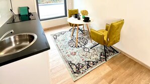 A modern kitchen with a sink, a dining area with a table and chairs, and a view through a large window.