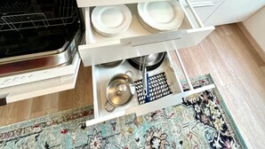 A kitchen with a built-in oven, a microwave, and a drawer with plates and a colander.